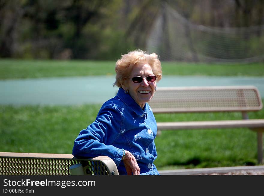 Senior woman sitting on a park bench. Senior woman sitting on a park bench.