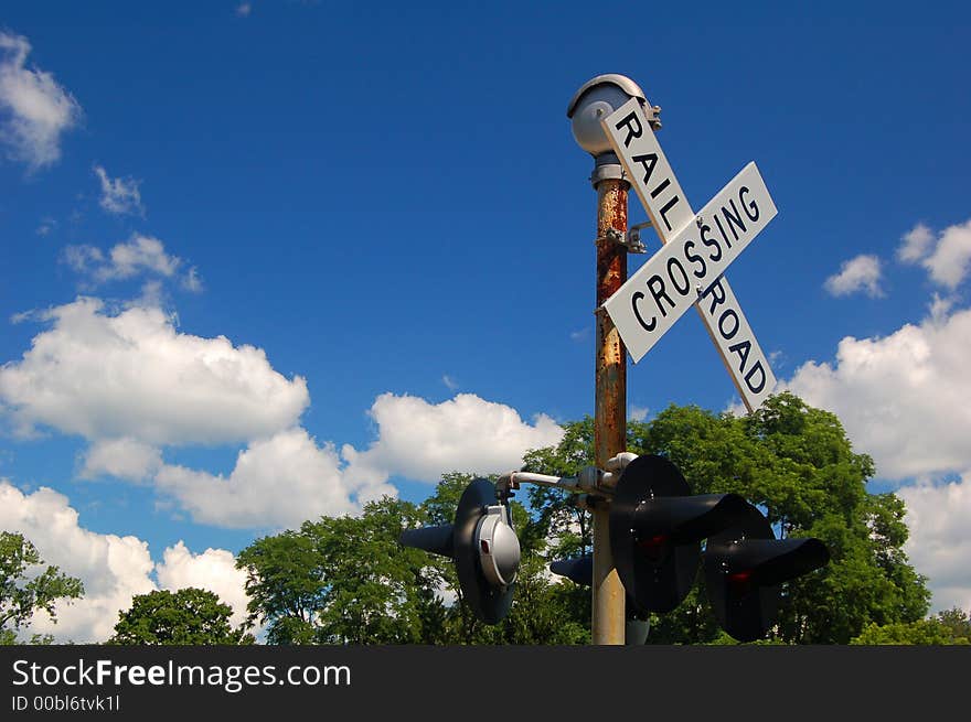 Rusted railroad crossing sign against very blue sky.