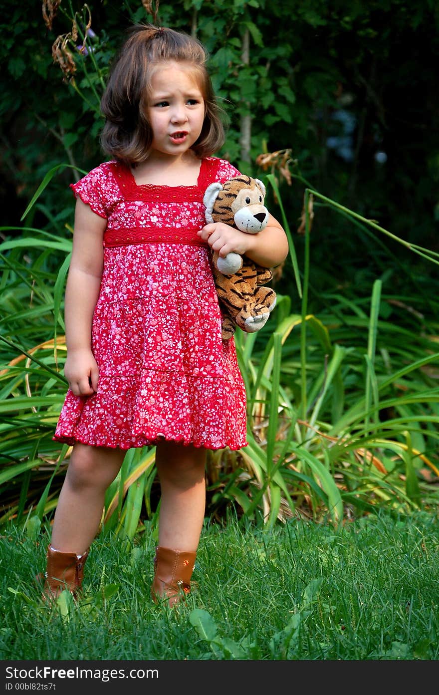 Four year old girl standing with her stuffed animal tiger. She has a worried look. Four year old girl standing with her stuffed animal tiger. She has a worried look.