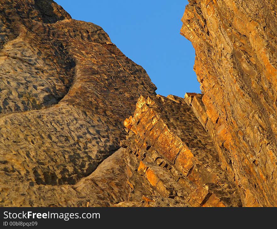 Orange seaside rocks against blue sky