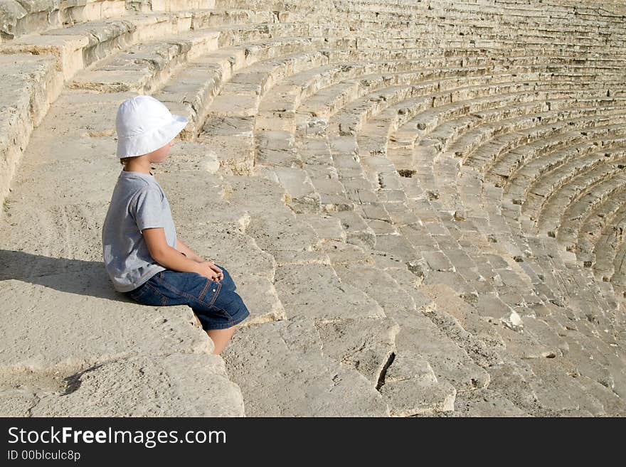 A small boy sitting in an amphitheatre