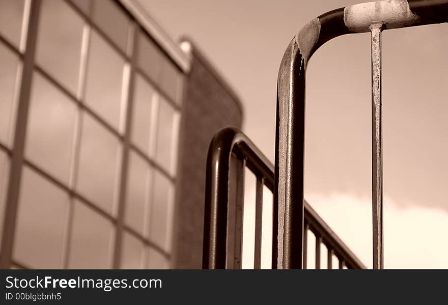 Sepia toned image of iron railing with building in background. Sepia toned image of iron railing with building in background