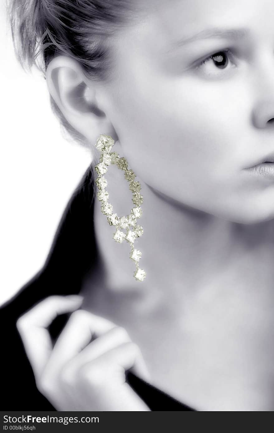 A model portrait in the studio presenting her earring in black and white keeping the earring in colour. A model portrait in the studio presenting her earring in black and white keeping the earring in colour