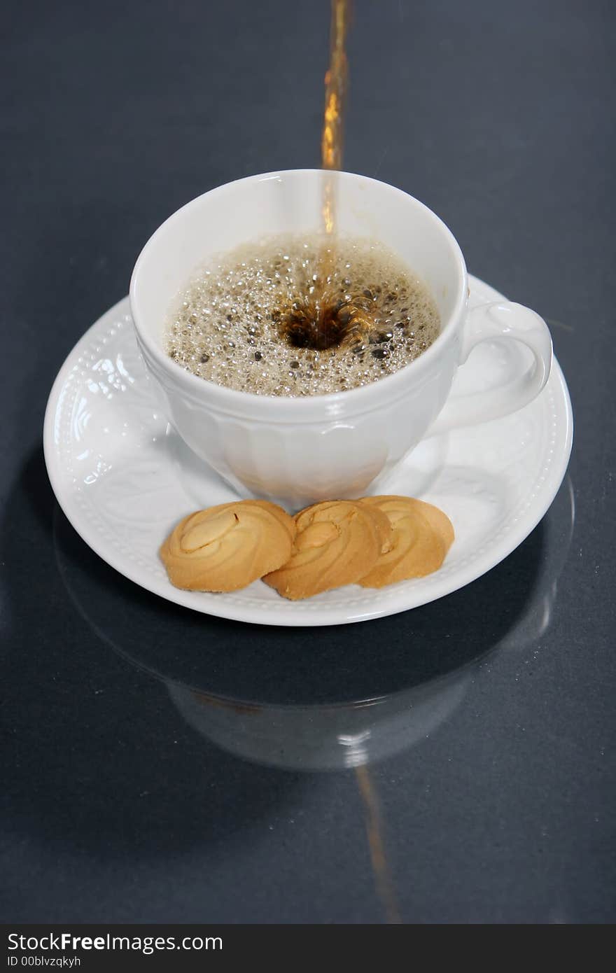 Pouring coffee into coffee cup and cookies isolated on black