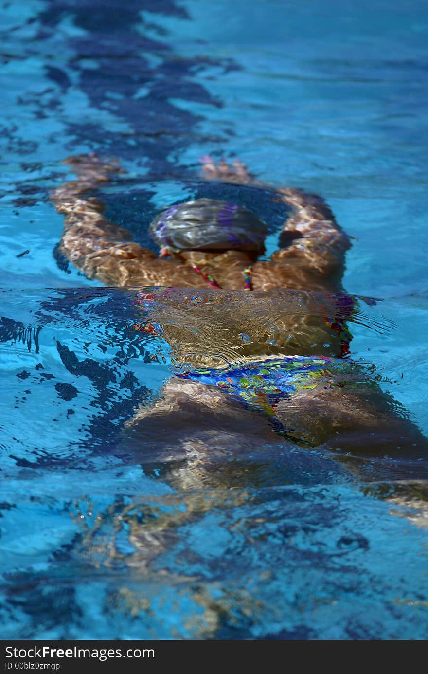 Young woman's back swimming underwater. Young woman's back swimming underwater.