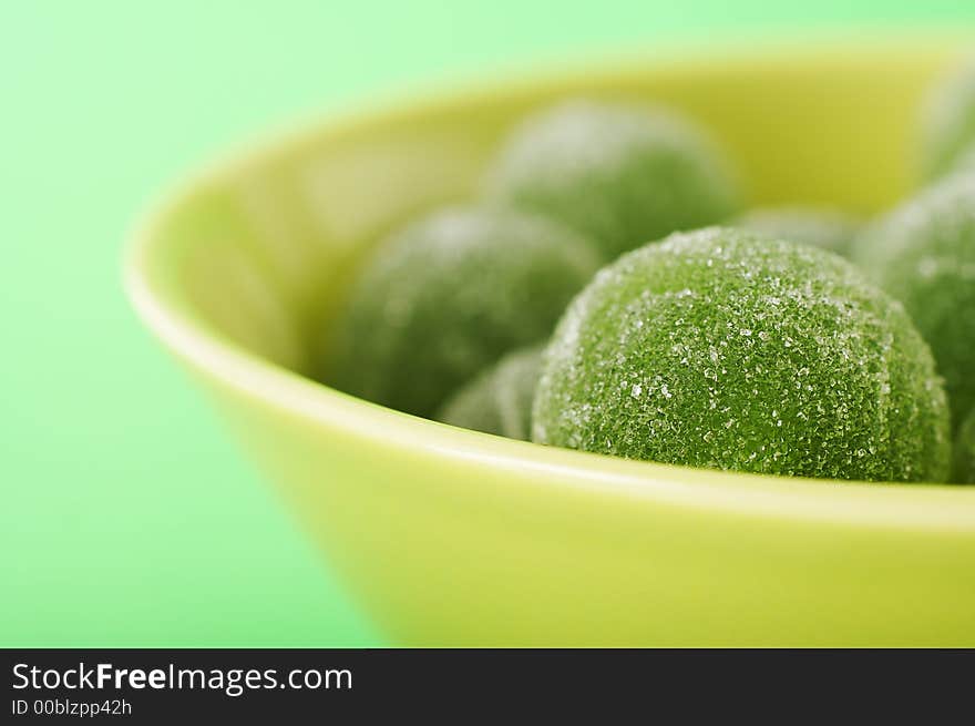 Green marmalade balls in the bowl on the green background