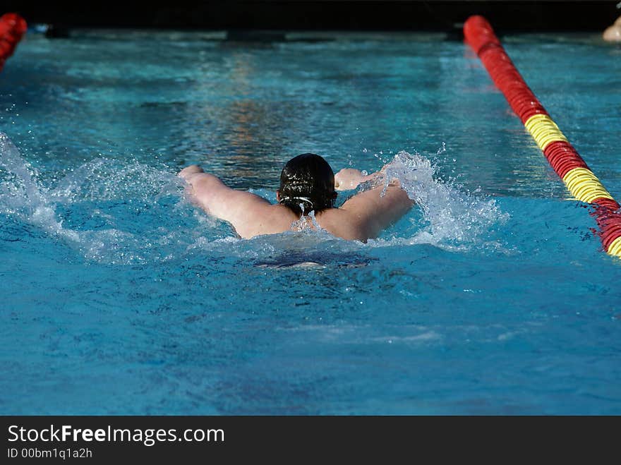 Young man swimming the butterfly event at a swim meet. Young man swimming the butterfly event at a swim meet.