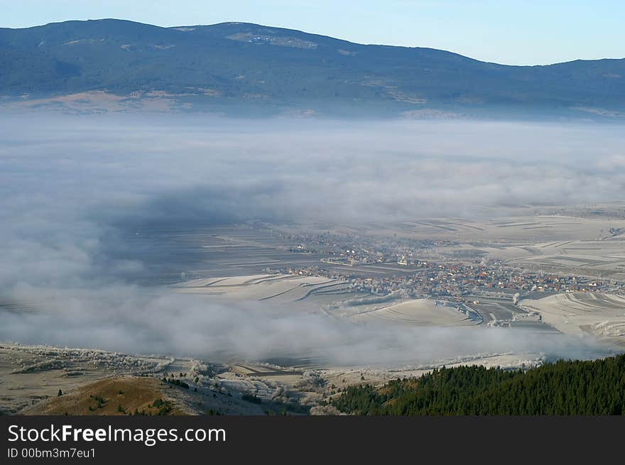 Heavy fog lifting from around a Transylvanian mountain village in a cold autumn morning. Heavy fog lifting from around a Transylvanian mountain village in a cold autumn morning