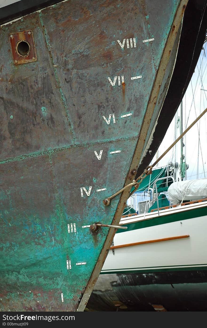 Bow of wooden sailboat with copper plated hull and depth markings in roman numerals. Bow of wooden sailboat with copper plated hull and depth markings in roman numerals.