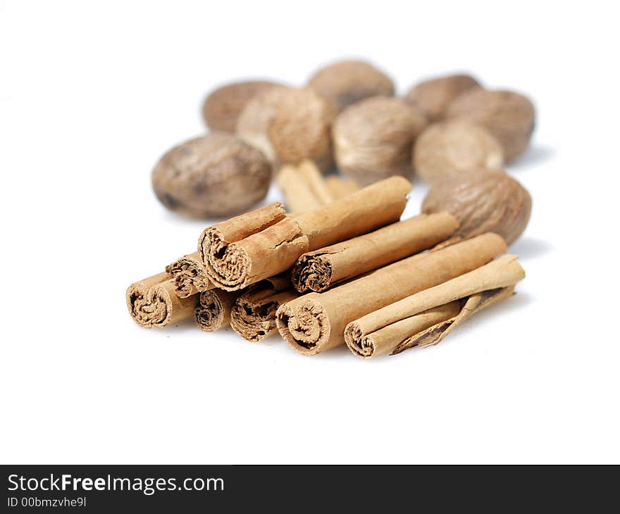 Cinnamon stick and whole nutmeg seed pods on white background