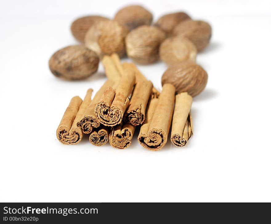 Cinnamon stick and whole nutmeg seed pods on white background