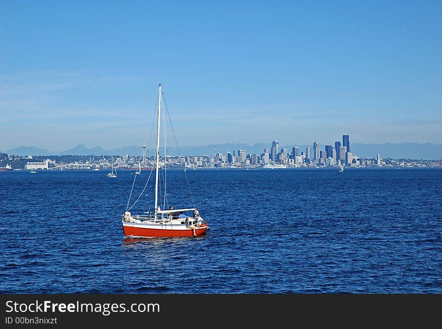 Red sailboat sailing away from Seattle, WA