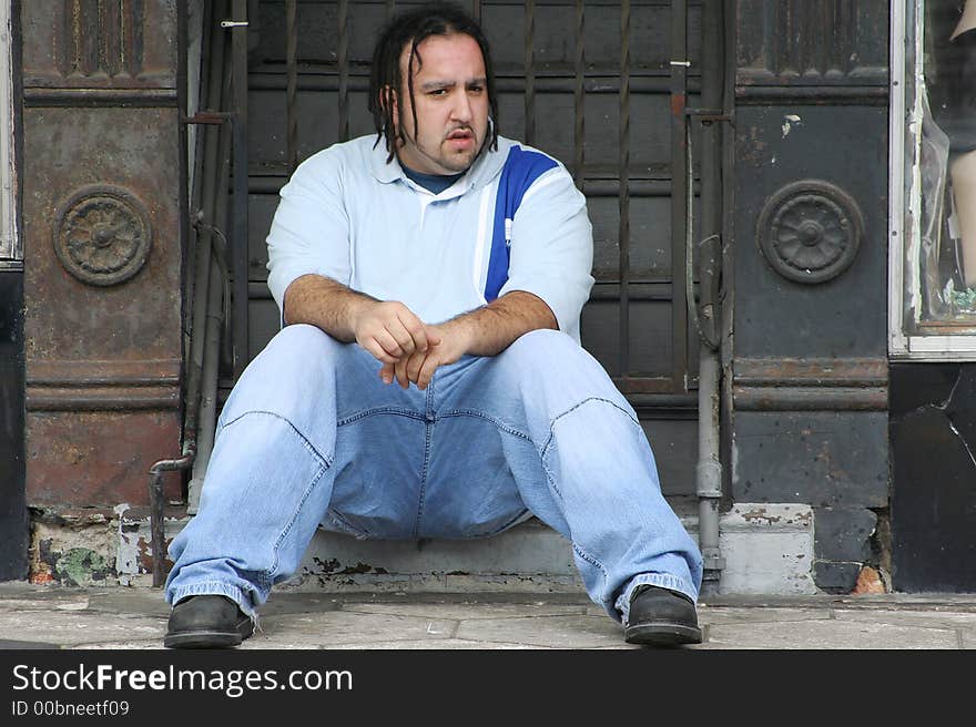 Photo of a young man sitting on the steps to a building. Photo of a young man sitting on the steps to a building