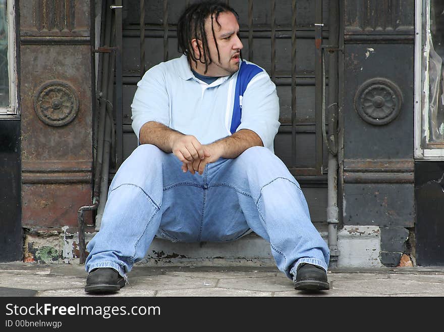 Photo of a young man sitting on the steps to a building. Photo of a young man sitting on the steps to a building