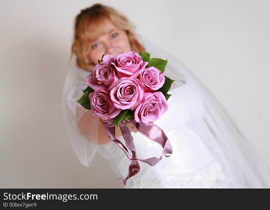 Beautiful bride and her bouquet of pink roses. Beautiful bride and her bouquet of pink roses.