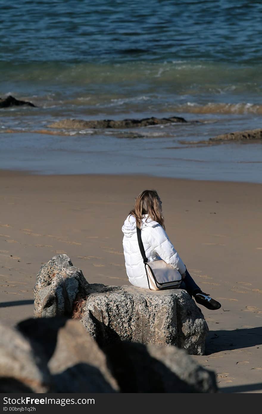 Woman sitting on rocks at the beach. Woman sitting on rocks at the beach