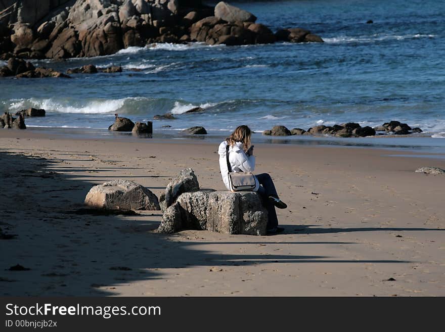 Woman sitting on rocks at the beach. Woman sitting on rocks at the beach