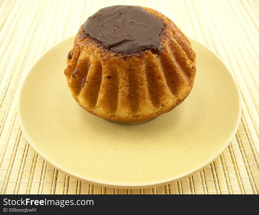 Beautiful tasty cake in chocolate on a plate on a bamboo napkin