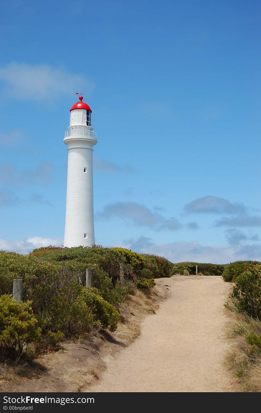 Path to white lighthouse against blue sky