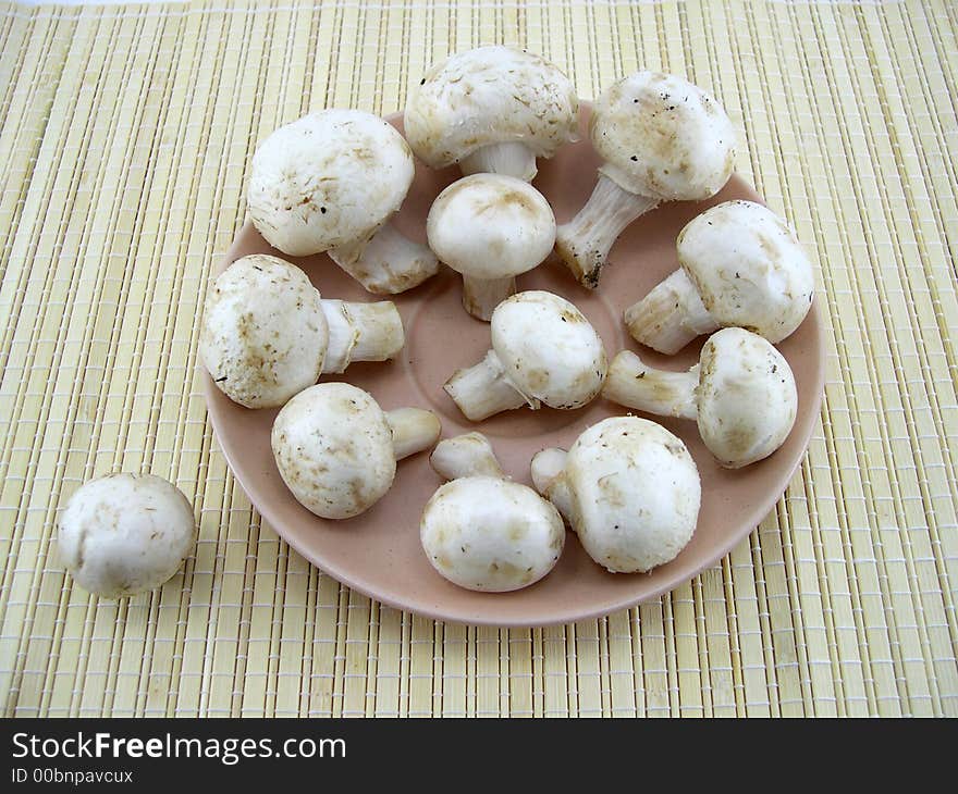 Beautiful white mushrooms champignons on a background of a bamboo napkin