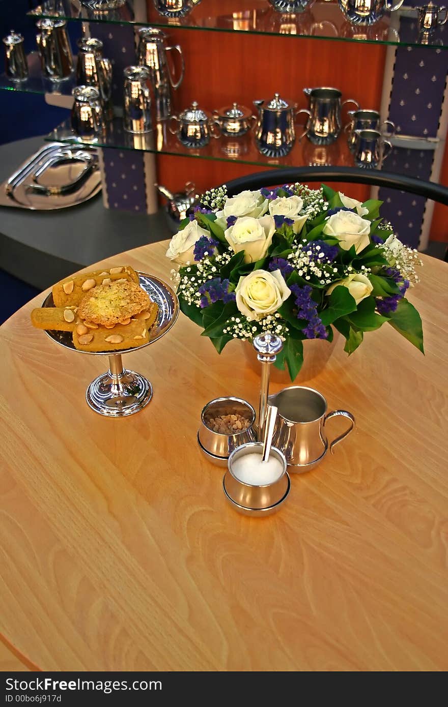 Table with chrome dish-ware behind. Table with chrome dish-ware behind