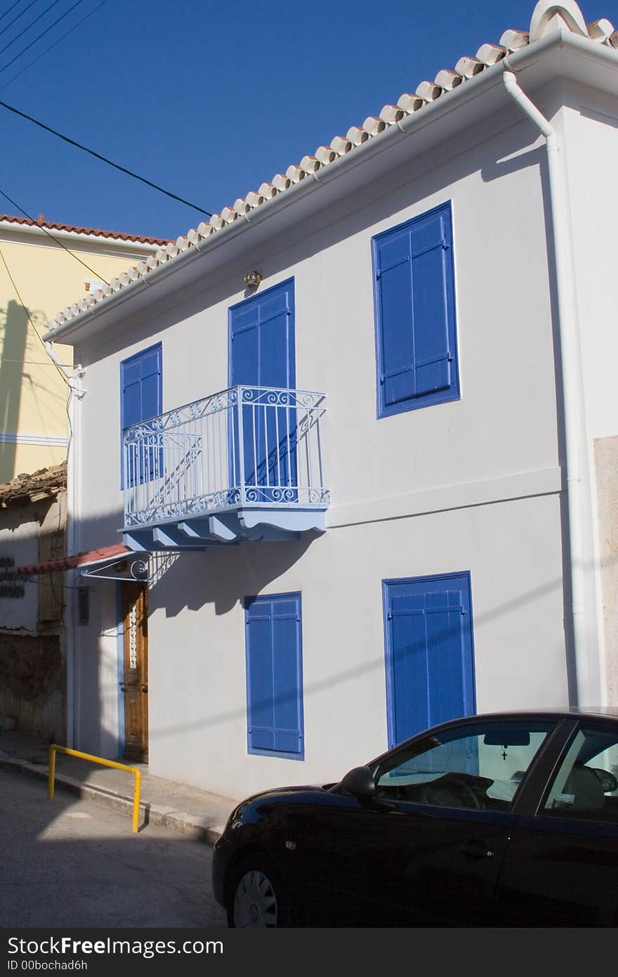 Facade of traditional greek house with balcony and shutters