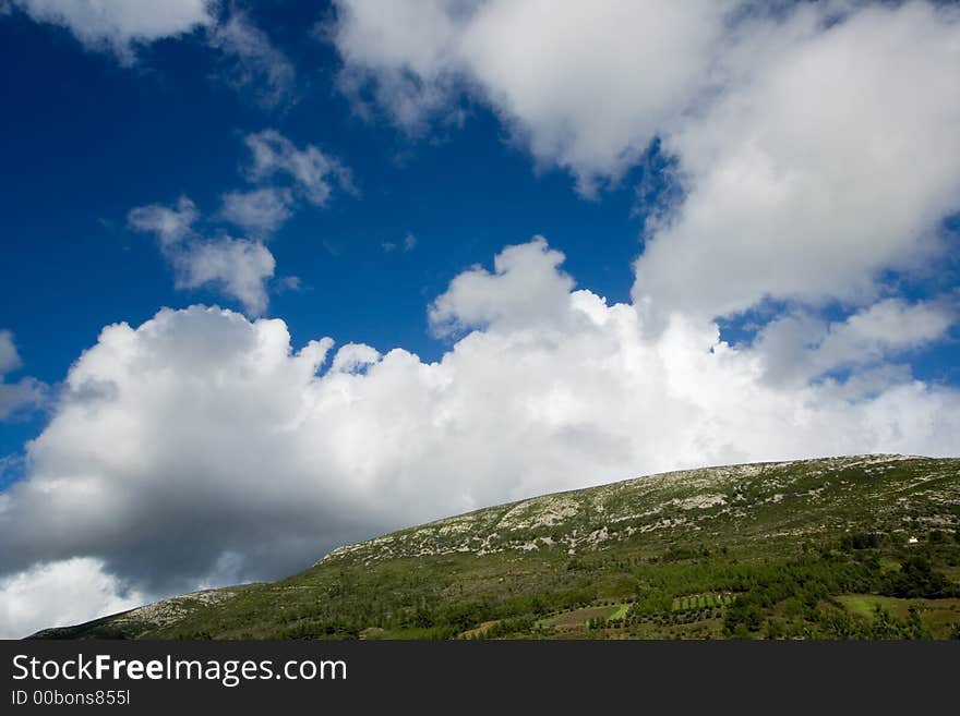 Mountain landscape - green filed, the blue sky and white clouds