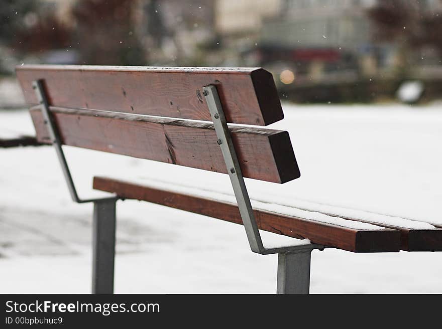 Abandoned park bench at winter while snowing. Shallow depth of field. Abandoned park bench at winter while snowing. Shallow depth of field