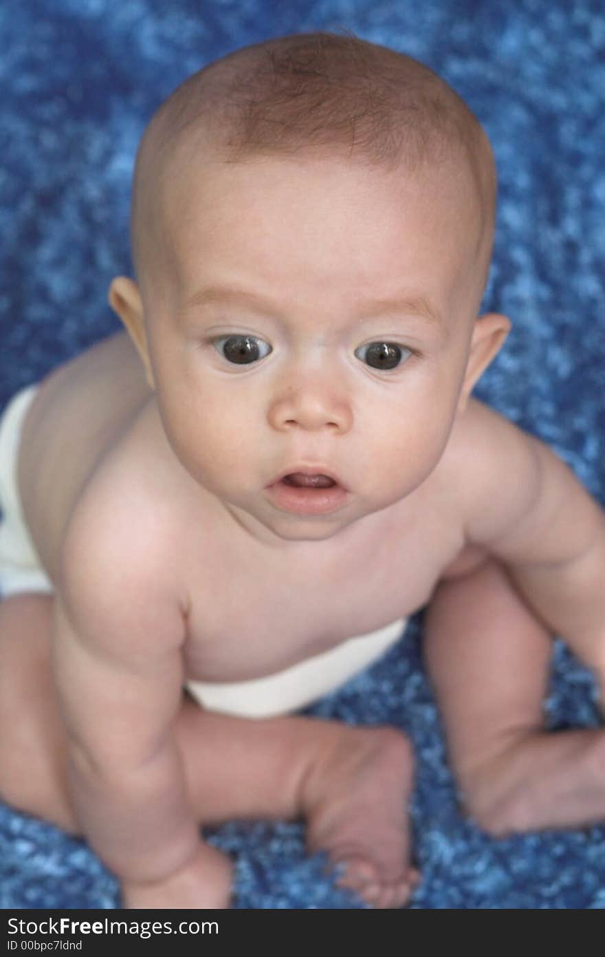 Image of cute baby boy sitting on a blue blanket