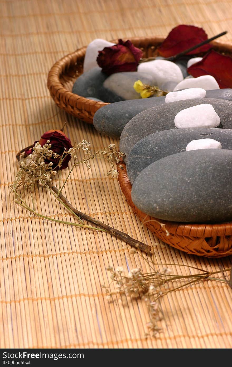 Natural pebbles and dried flowers on the rattan background. Suitable for spa and relaxation setting. Natural pebbles and dried flowers on the rattan background. Suitable for spa and relaxation setting.