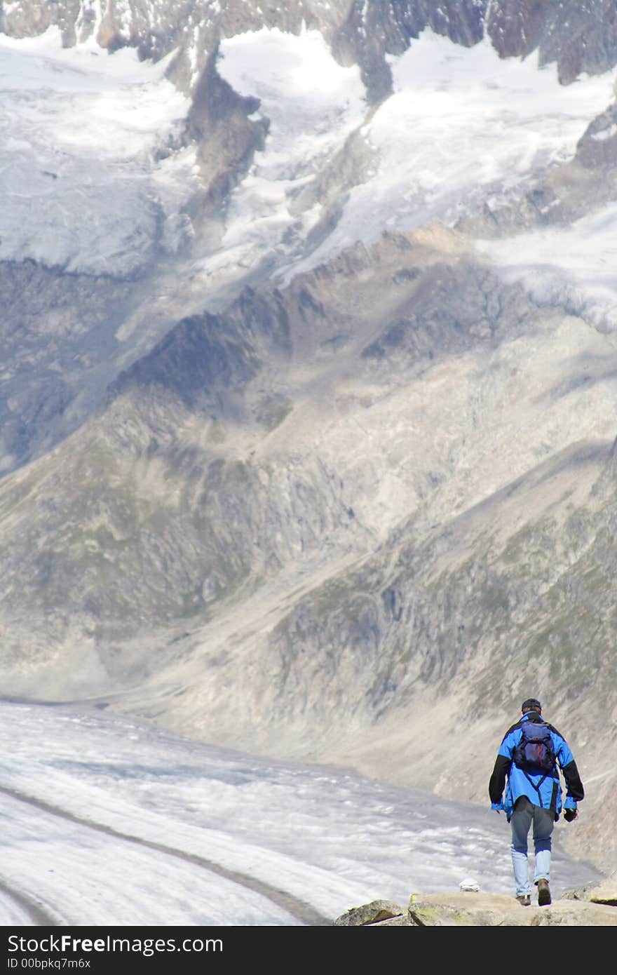 Lone man climbing a mountain covered with patches of snow. Signs of global warming. Lone man climbing a mountain covered with patches of snow. Signs of global warming.