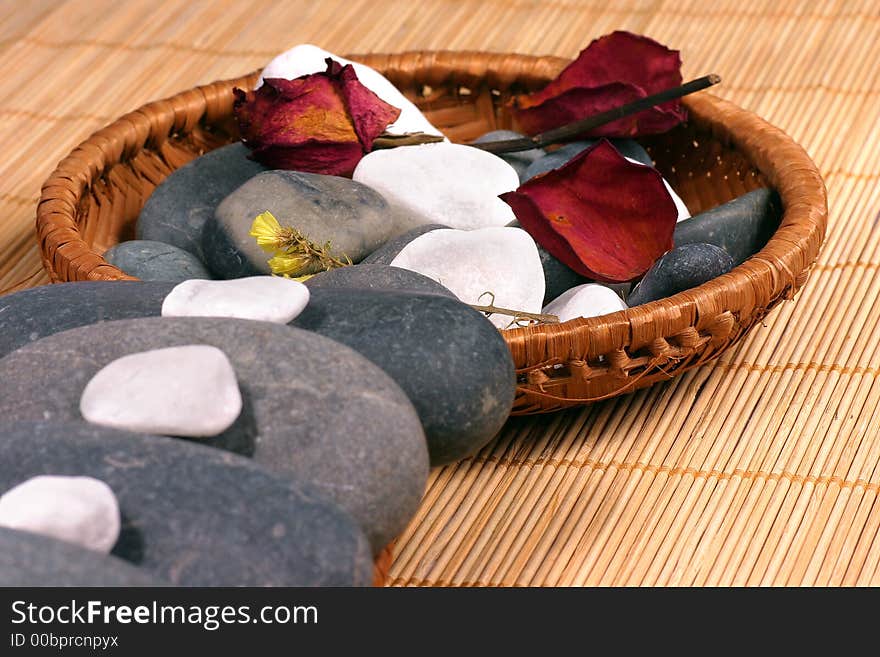 Natural pebbles and dried flowers on the rattan background. Suitable for spa and relaxation setting. Natural pebbles and dried flowers on the rattan background. Suitable for spa and relaxation setting.