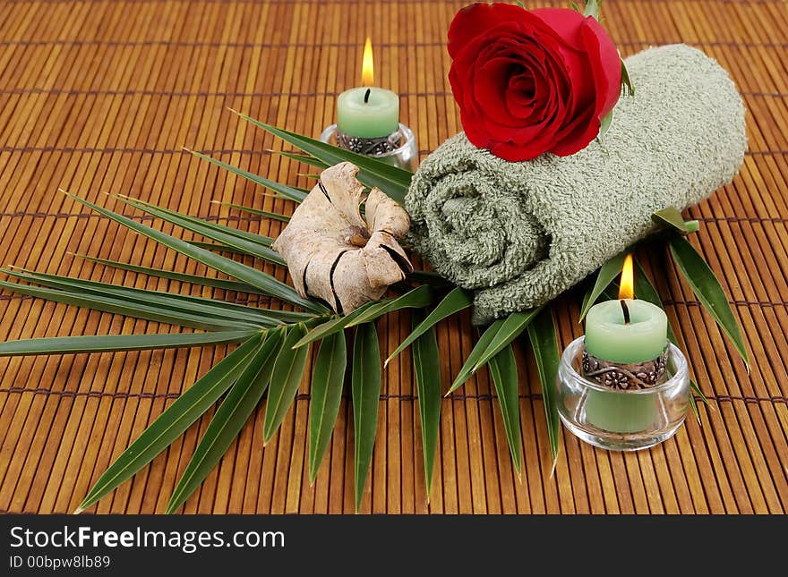 Rose, palm frond, towel, and candles on bamboo