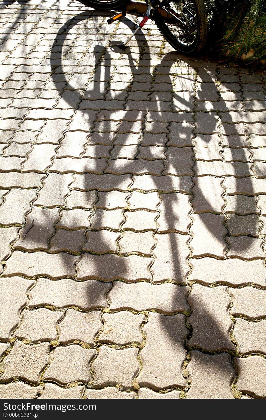 Thr shadow of the bicycle, falling over a regular pattern of cobble. Thr shadow of the bicycle, falling over a regular pattern of cobble