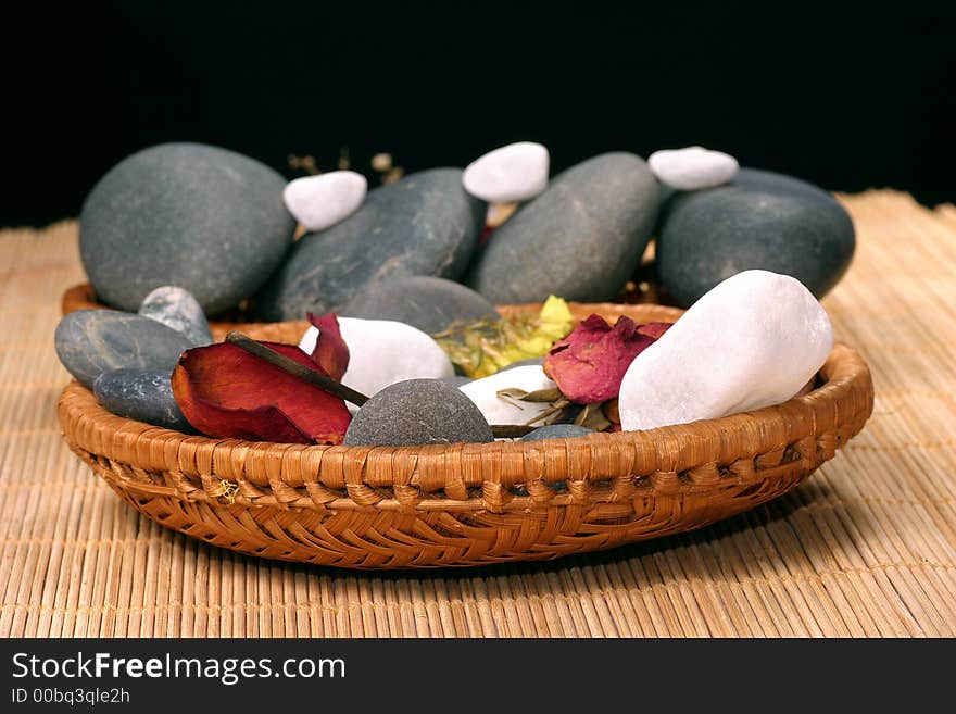 Natural pebbles and dried flowers on the rattan background. Suitable for spa and relaxation setting. Natural pebbles and dried flowers on the rattan background. Suitable for spa and relaxation setting.