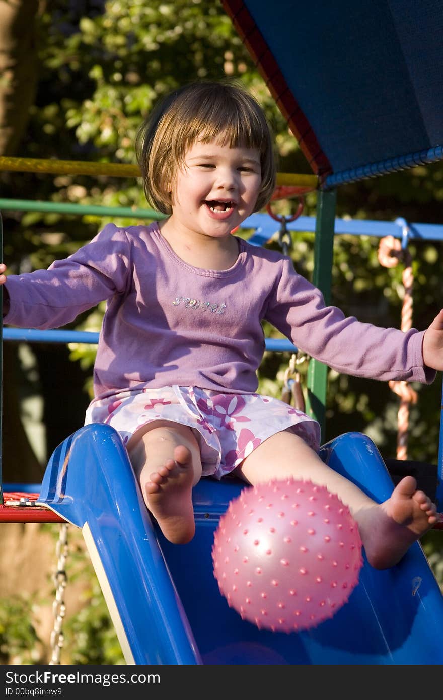 Cute little brunette girl playing with  ball on the slie. Cute little brunette girl playing with  ball on the slie