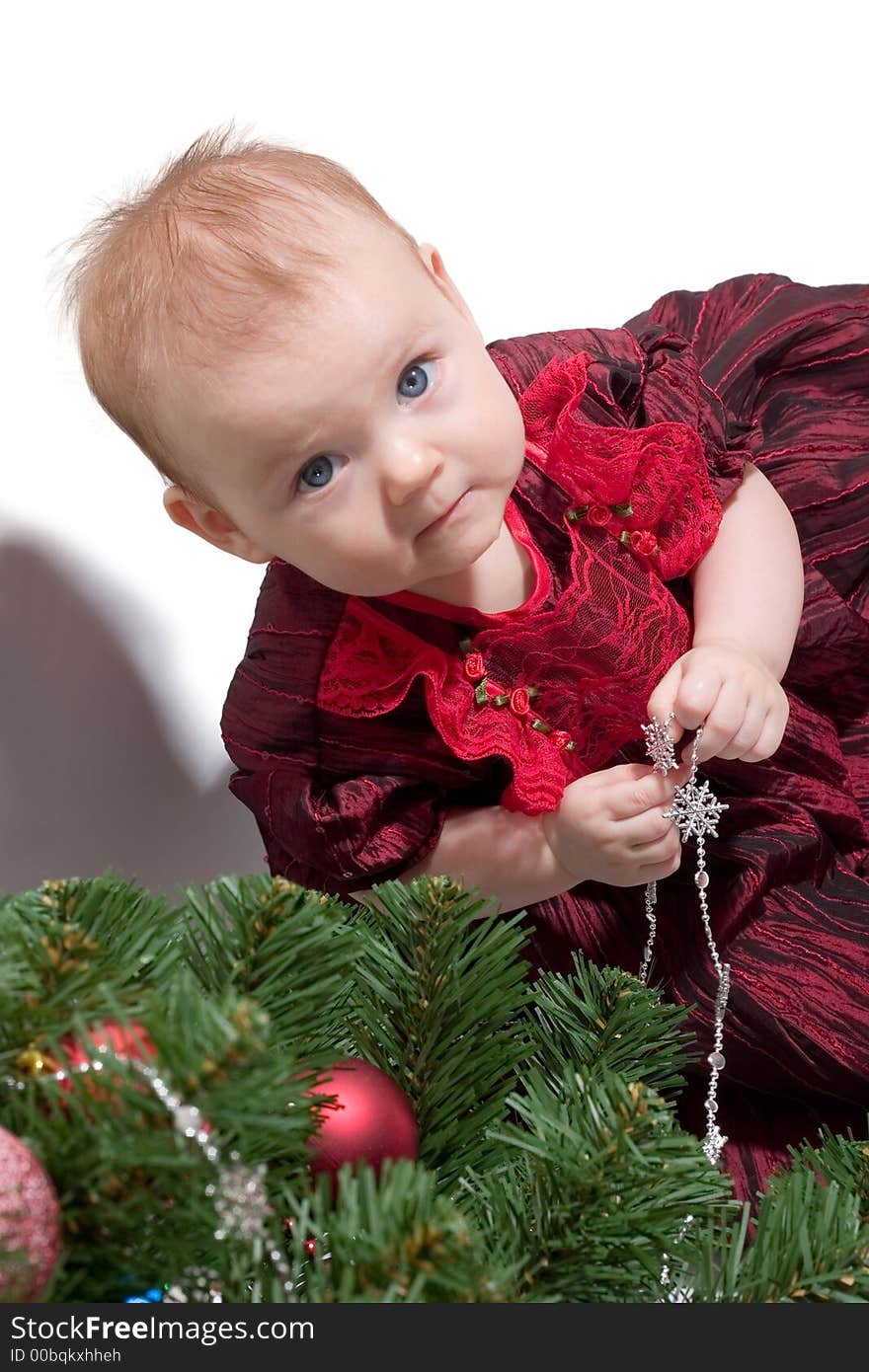 Little baby girl in formal red dress standing next to the Christmas tree. Copy space is on the right top. Little baby girl in formal red dress standing next to the Christmas tree. Copy space is on the right top.