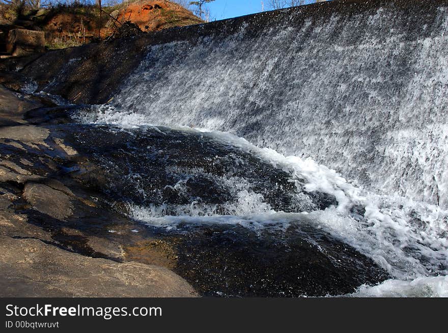 Water running over a dam and over boulders. Water running over a dam and over boulders