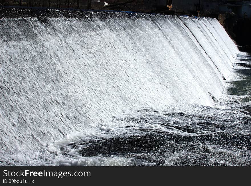 Water running over a dam and over boulders. Water running over a dam and over boulders