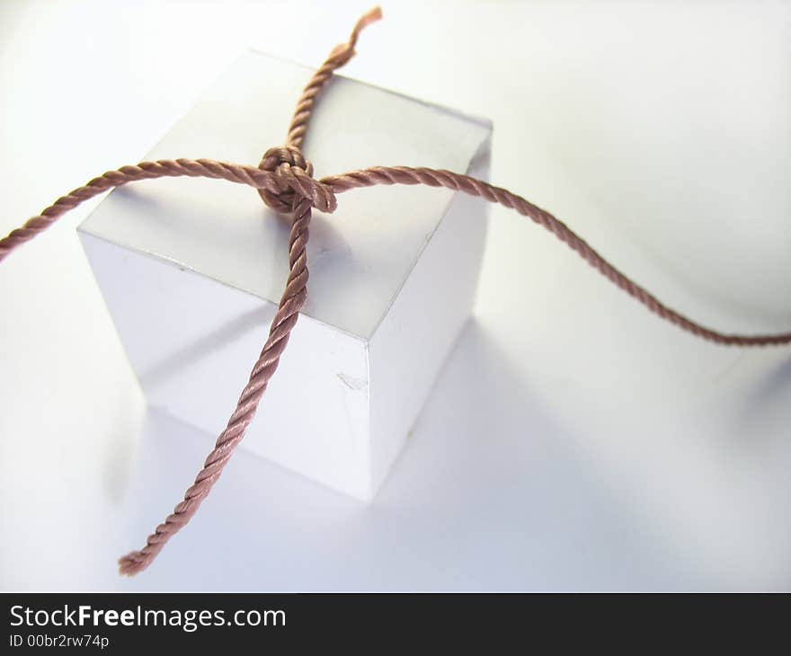 The fastened cord laying on a cardboard cube. The fastened cord laying on a cardboard cube.