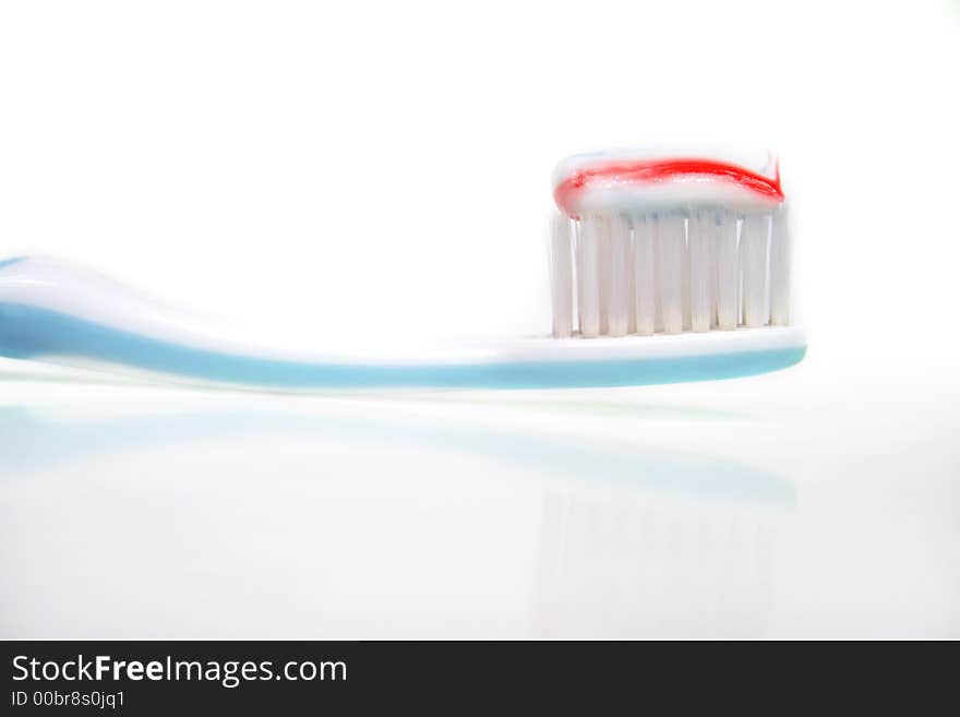 A toothbrush with toothpaste in front of white background