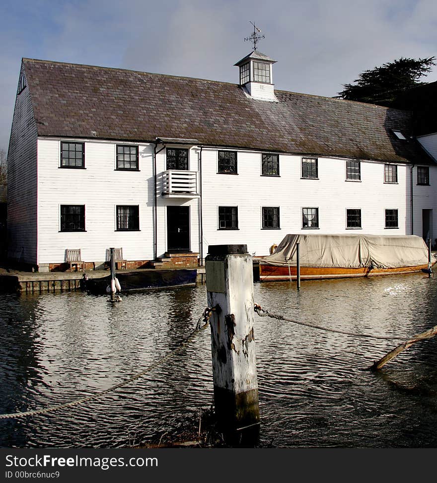 Winter scene of a an Historic Riverside Mill House with Boats moored to the front