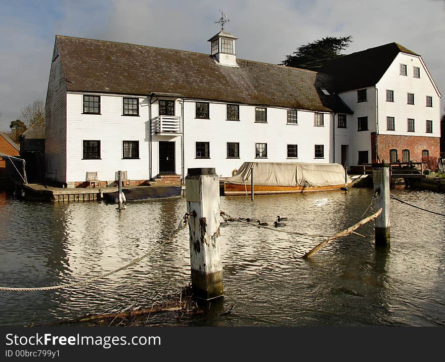 Winter scene of a an Historic Riverside Mill House with Boats moored to the front