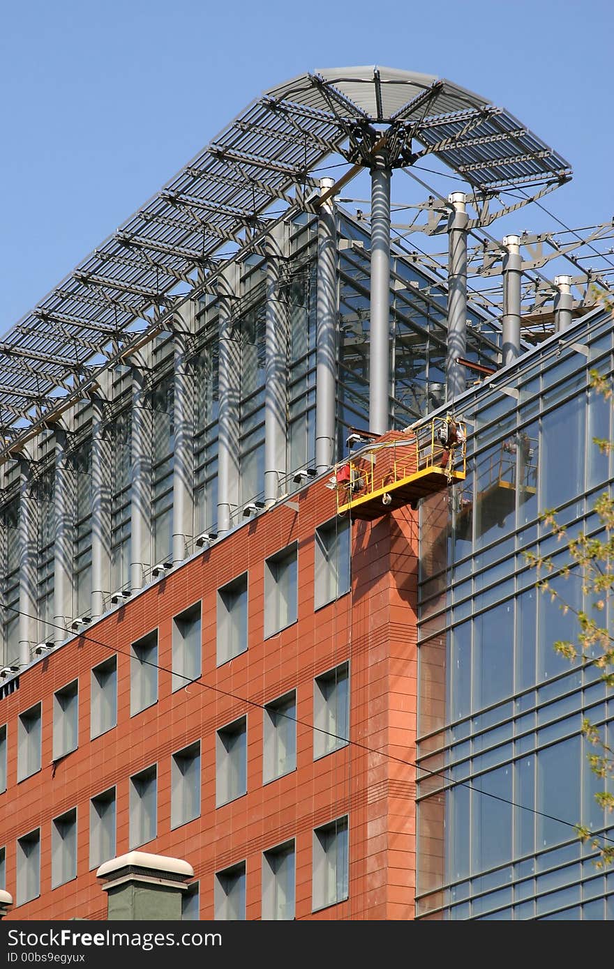 The closing stage of construction the business center, a building from glass and metal on a background of the blue sky. The closing stage of construction the business center, a building from glass and metal on a background of the blue sky