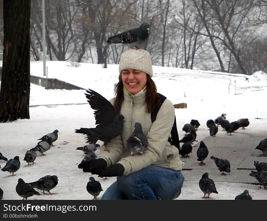 Many pigeons are sitting on a young girl. Many pigeons are sitting on a young girl