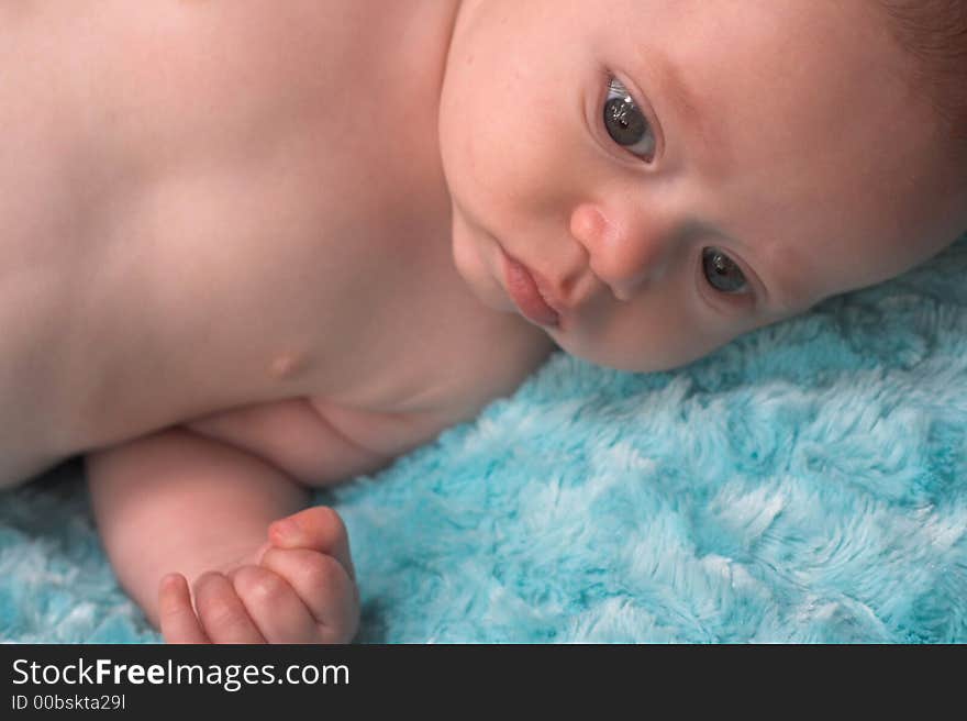 Image of baby boy lying on a fuzzy turquoise blanket. Image of baby boy lying on a fuzzy turquoise blanket