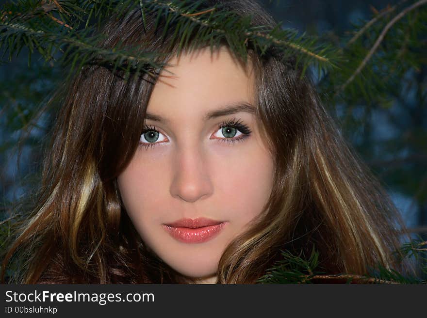 Close up of the girl the brunette which thoughtfully looks from behind the branches. Close up of the girl the brunette which thoughtfully looks from behind the branches