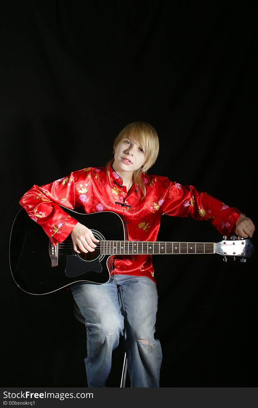 A young woman playing her guitar with expression. A young woman playing her guitar with expression.