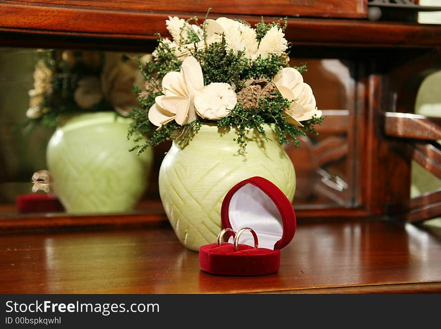 Gold wedding rings in a red casket on a background flowers