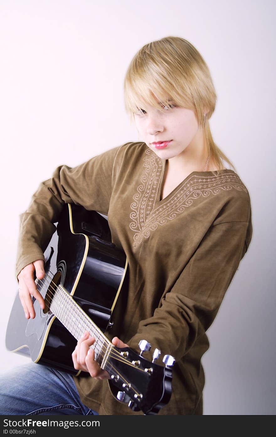 A young woman playing her guitar with expression. A young woman playing her guitar with expression.